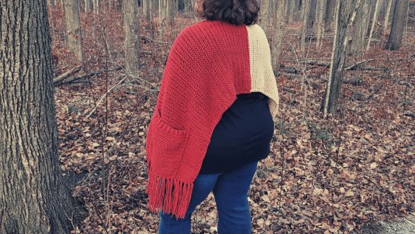 a woman wearing a cozy pocket crochet shawl 