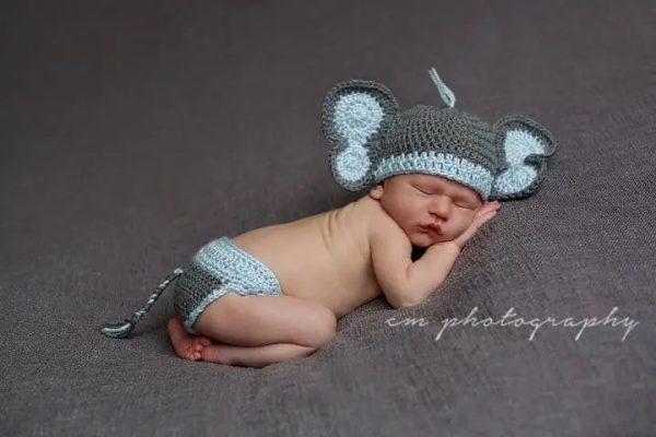a baby wearing an elephant crochet hat and diaper cover with tail