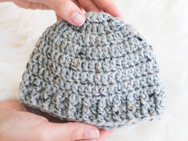 hands holding the parker crochet baby hat