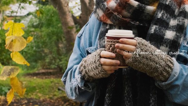 a person holding a cup and wearing susan wrist warmers by sunflower cottage crochet